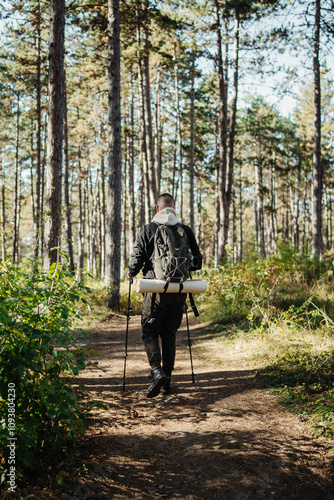 Young caucasian man hiking or trekking through the forest 