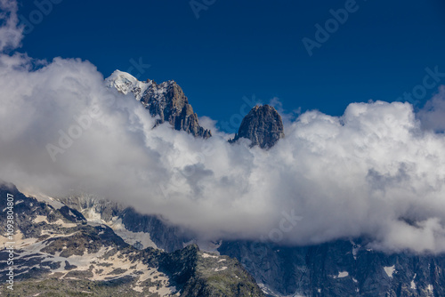 Petit Dru granite mountain wall and summit in Chamonix valley, french Alps. Prominent mountain peak in the Alps, stunning landscape view of the rocky peak covered with clouds, snow and ice