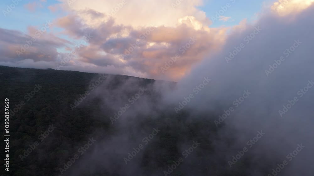Toma aerea sobre la montaña cubierta de grandes nubes naranjas Toma aerea sobre la montaña cubierta de grandes nubes naranjas