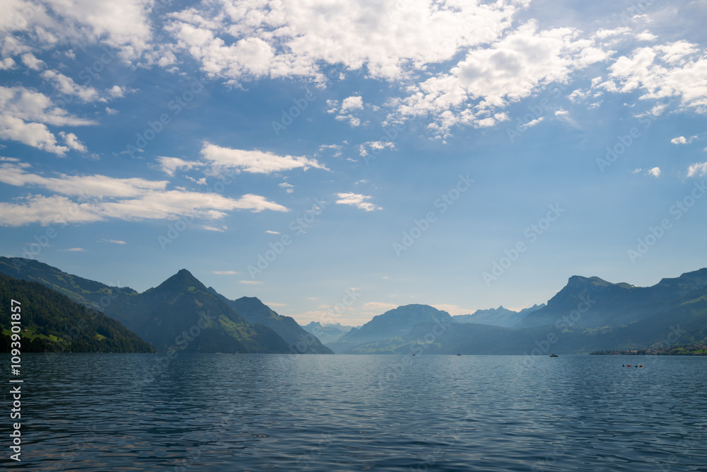 Alps mountain background. Swiss Alps mountain on sunny day. Mountain under clouds in blue sky. Blue nature background. Blue lake with sky near blue mountain. Alps mountain background. Swiss Alps mountain on sunny day. Mountain under clouds in blue sky. Blue nature background. Blue lake with sky near blue mountain.