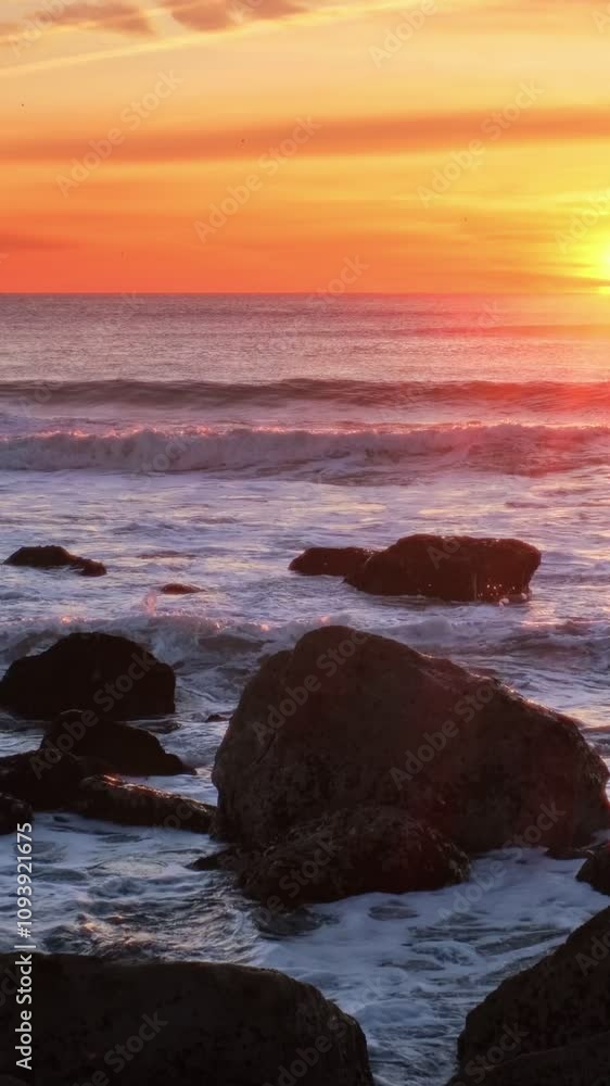 Atlantic ocean sunset with waves and rocks and surfers silhouettes in water at Costa da Caparica, Portugal. Camera pan Atlantic ocean sunset with waves and rocks and surfers silhouettes in water at Costa da Caparica, Portugal. Camera pan