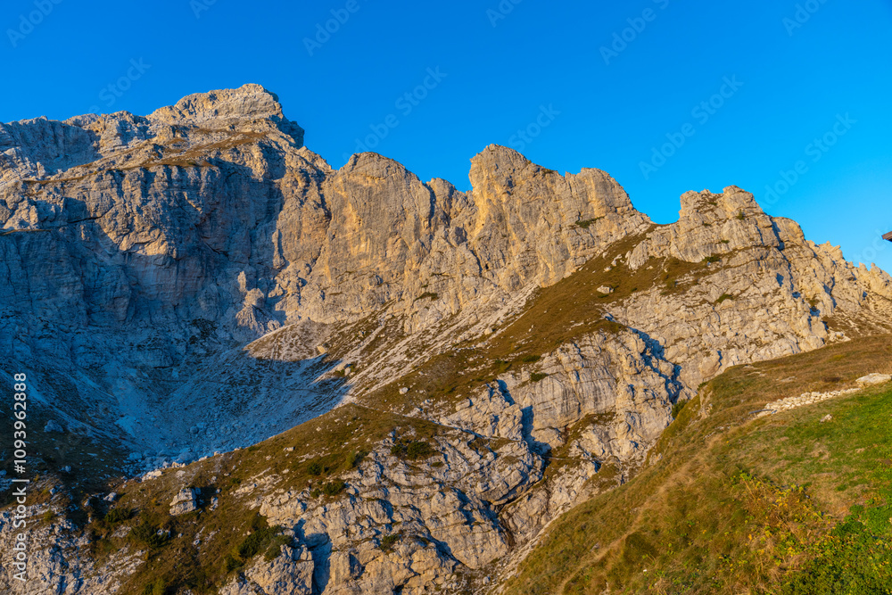 Sunset in the mountains. Red and orange burning sky horizon behind the alpine mountain range. Rocky mountain peaks of the Dolomites at sunset and dawn at sunrise light sunrays going through the clouds Sunset in the mountains. Red and orange burning sky horizon behind the alpine mountain range. Rocky mountain peaks of the Dolomites at sunset and dawn at sunrise light sunrays going through the clouds