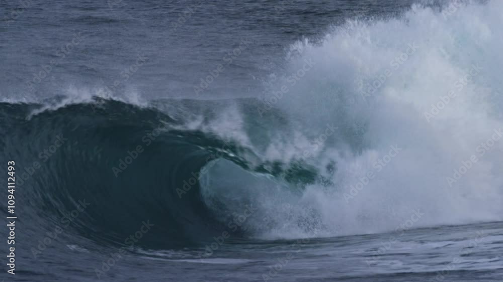 Atlantic wave barrels smoothly, rolling forward in slow motion under stormy skies Atlantic wave barrels smoothly, rolling forward in slow motion under stormy skies