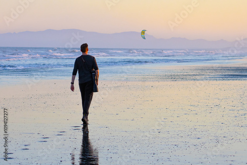 Photography A man photographer walks on stunning vast, long Waikuku Beach next to Ashley river with impressive mountain in the background, Canterbury, Christchurch, New Zealand, south island