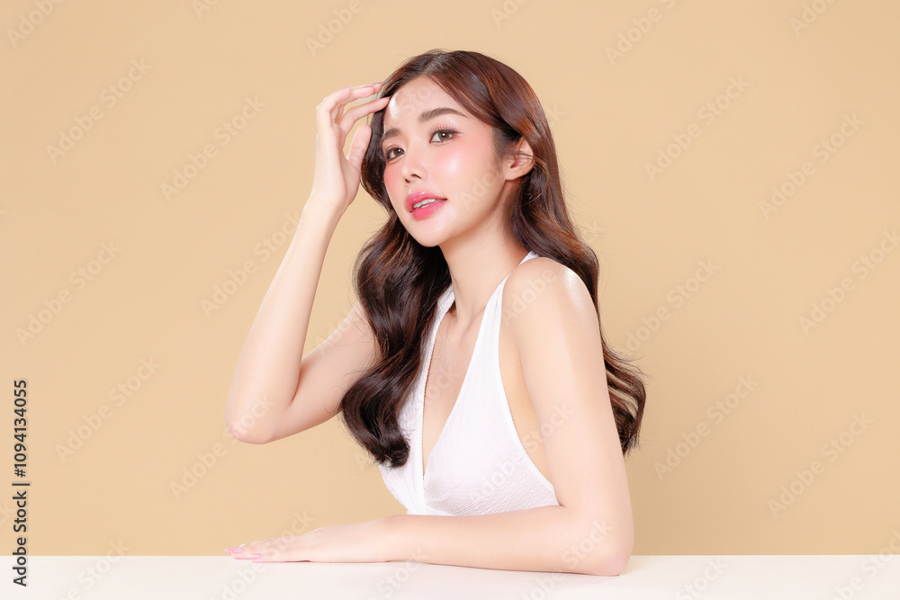 Pretty Asian beauty woman curly long hair with Korean makeup glowing face and healthy facial skin portrait smile on isolated beige background. Cosmetology ,Plastic surgery. Pretty Asian beauty woman curly long hair with Korean makeup glowing face and healthy facial skin portrait smile on isolated beige background. Cosmetology ,Plastic surgery.