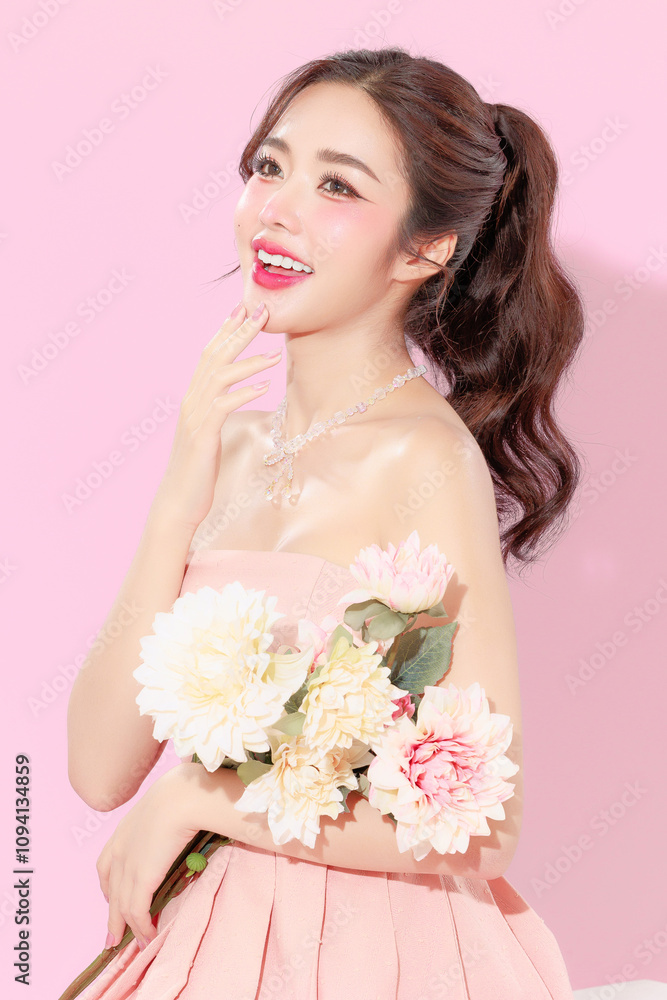 Pretty Asian beauty woman with Korean makeup glowing face and healthy facial skin portrait smile holding flower on isolated pink background. Cosmetology ,Plastic surgery. Pretty Asian beauty woman with Korean makeup glowing face and healthy facial skin portrait smile holding flower on isolated pink background. Cosmetology ,Plastic surgery.