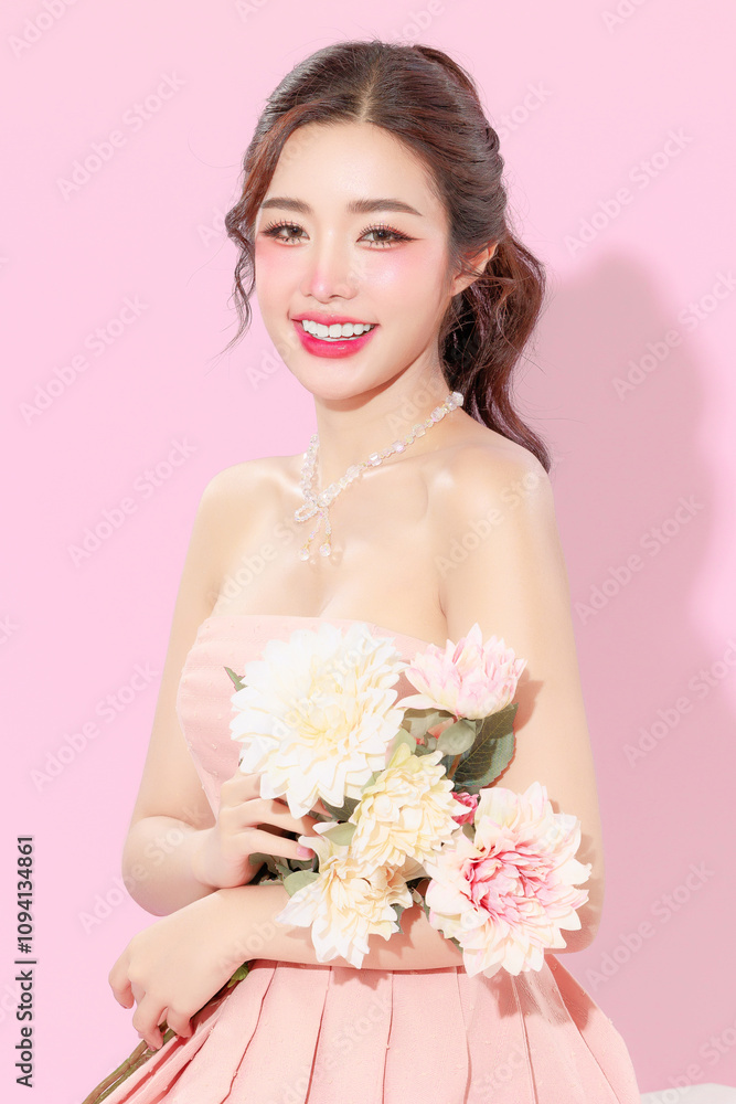 Pretty Asian beauty woman with Korean makeup glowing face and healthy facial skin portrait smile holding flower on isolated pink background. Cosmetology ,Plastic surgery. Pretty Asian beauty woman with Korean makeup glowing face and healthy facial skin portrait smile holding flower on isolated pink background. Cosmetology ,Plastic surgery.