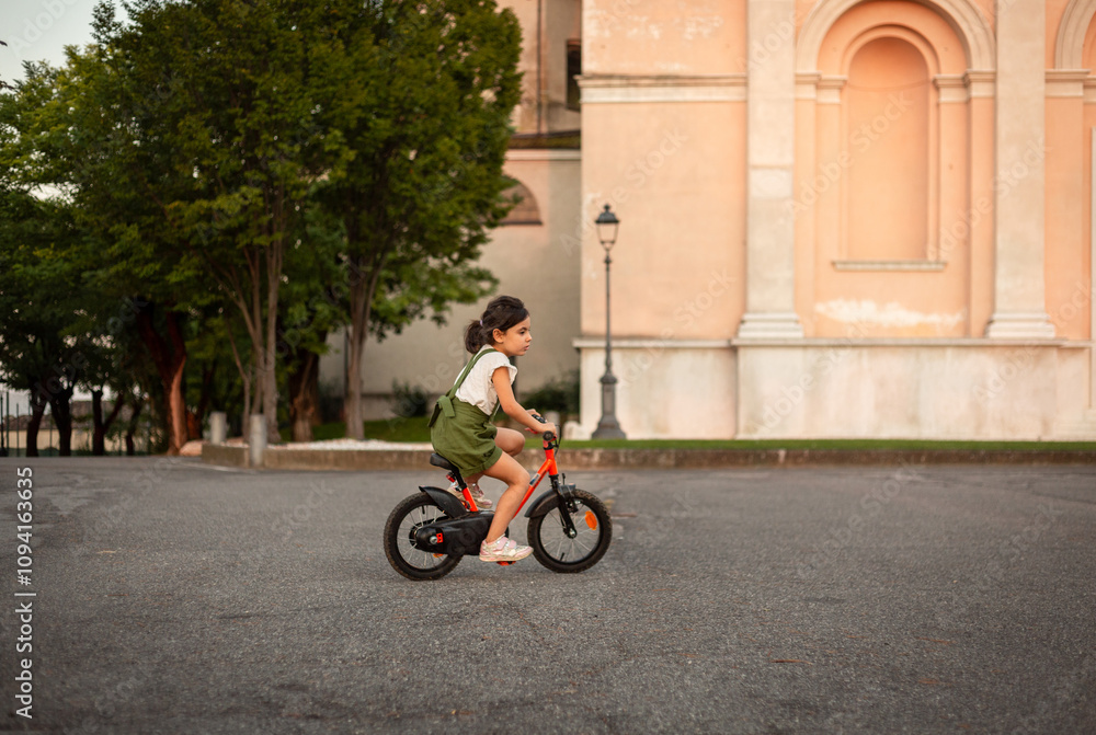 wide angle view of small girl riding bicycle on the square of the town