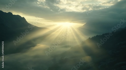 Sun rays shining through clouds in a misty mountain valley.