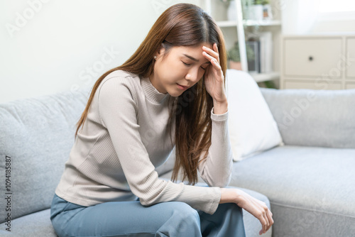 Depressed anxiety asian young woman, girl frustrated closed eyes, touching face suffering stressed, sick, tired, crisis sitting on sofa from headache, migraine pain tension problem health care concept