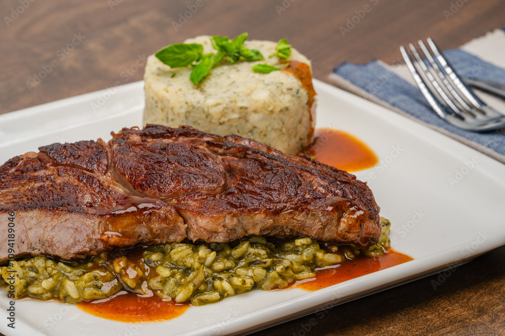 Grilled Beef Entrecote. Entrecote with sauce on a bed of green rice. Close-up. Grilled Beef Entrecote. Entrecote with sauce on a bed of green rice. Close-up.
