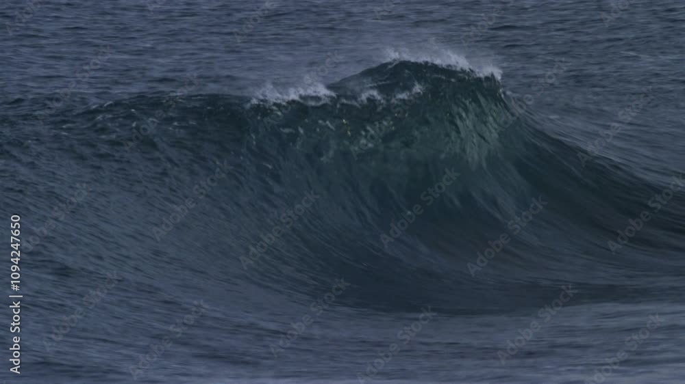 Ocean wave builds and curls, forming a smooth barrel in slow motion on a stormy Atlantic day Ocean wave builds and curls, forming a smooth barrel in slow motion on a stormy Atlantic day
