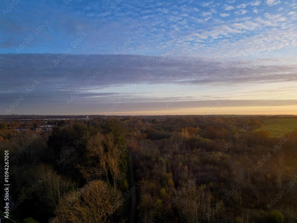 Aerial view of a serene autumn landscape with a vast forest under a partly cloudy sky during sunset Aerial view of a serene autumn landscape with a vast forest under a partly cloudy sky during sunset