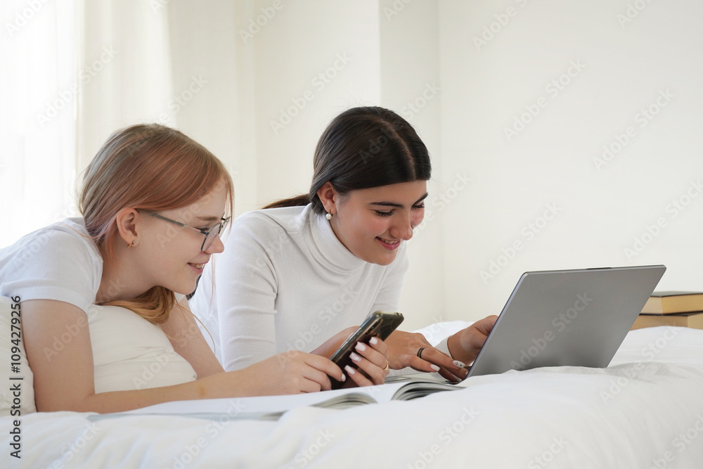 Preteen school Girls sitting on the bed and working with laptop looking on screen using gadget doing homework. Children learning at home. Back to school. Preteen school Girls sitting on the bed and working with laptop looking on screen using gadget doing homework. Children learning at home. Back to school.