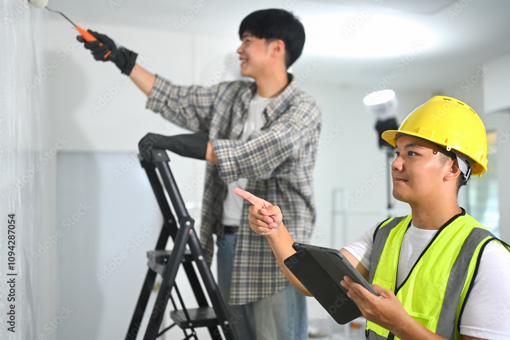 Two workers collaborating on an indoor painting project Two workers collaborating on an indoor painting project
