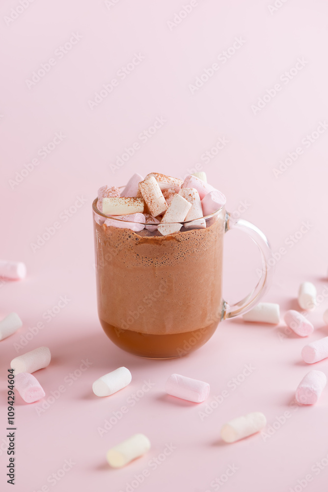 Hot chocolate cocoa drink with marshmallows, coconut milk and cinnamon in clear glass on a pink background. Vegan, sugar and lactose free. Vertical orientation. Hot chocolate cocoa drink with marshmallows, coconut milk and cinnamon in clear glass on a pink background. Vegan, sugar and lactose free. Vertical orientation.