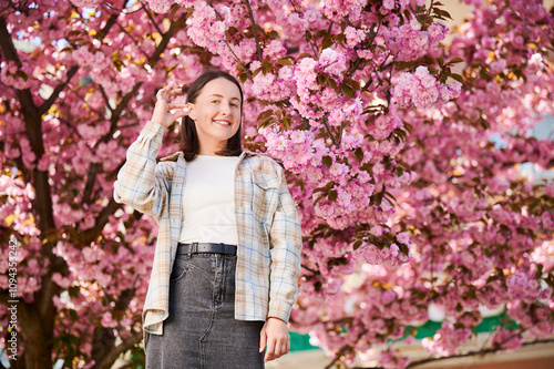 Woman allergic suffering from seasonal allergy at spring. Young happy woman showing allergy pill, posing in blossoming garden at springtime. Antihistamine medication concept