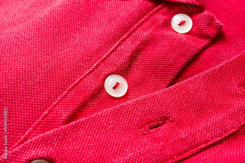 Buttons on the collar of a red shirt.
