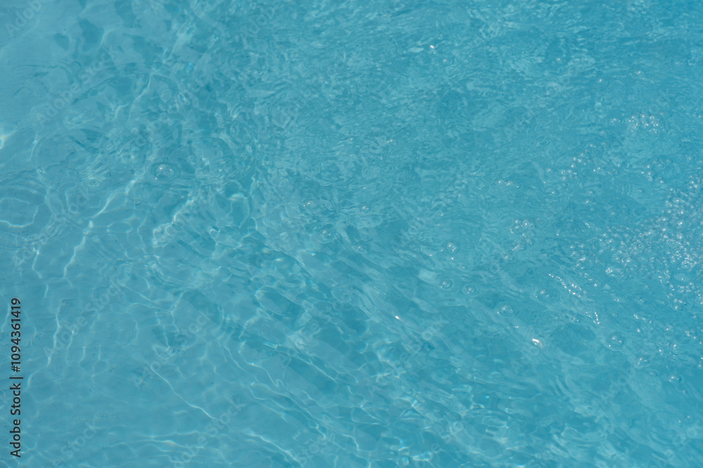 Obraz premium Blue water with ripples on the surface. Defocus blurred transparent blue colored clear calm water surface texture with splashes and bubbles. Water waves with shining pattern texture background.