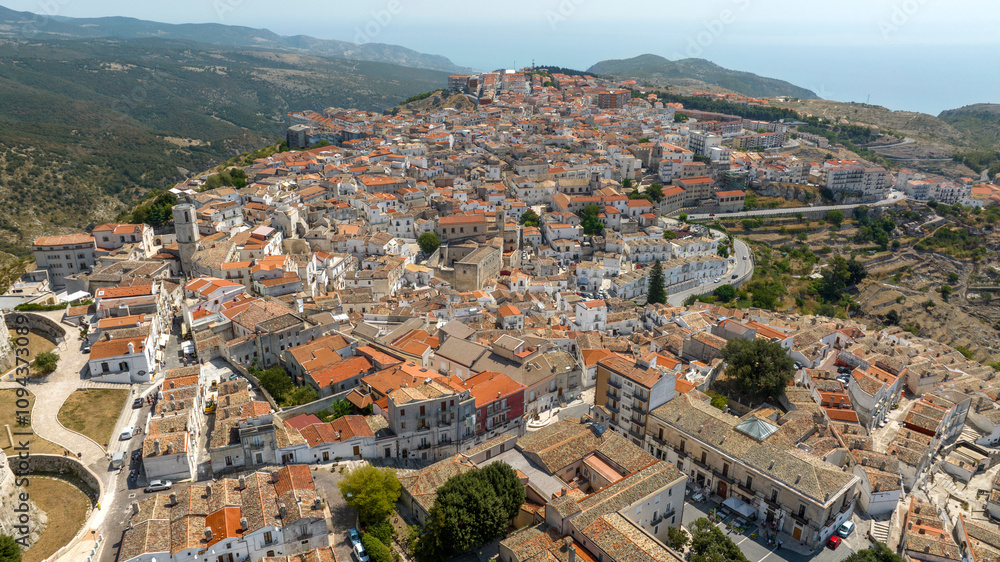 Obraz premium Aerial view of houses and buildings in the historic center of Monte Sant'Angelo, in the province of Foggia, Apulia. It is a typical village of Southern Italy. In background is the Mediterranean sea.