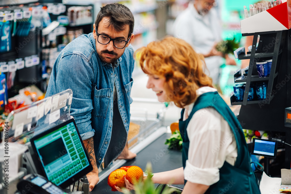 Customer watching cashier scanning oranges at supermarket checkout Customer watching cashier scanning oranges at supermarket checkout
