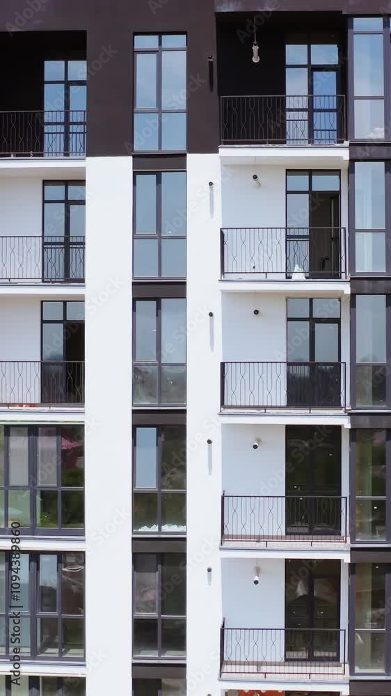 Black and white block of flats. Front view of a modern multi-storey building with glazed balconies in the city. Beautiful new housing apartments. Vertical video Black and white block of flats. Front view of a modern multi-storey building with glazed balconies in the city. Beautiful new housing apartments. Vertical video