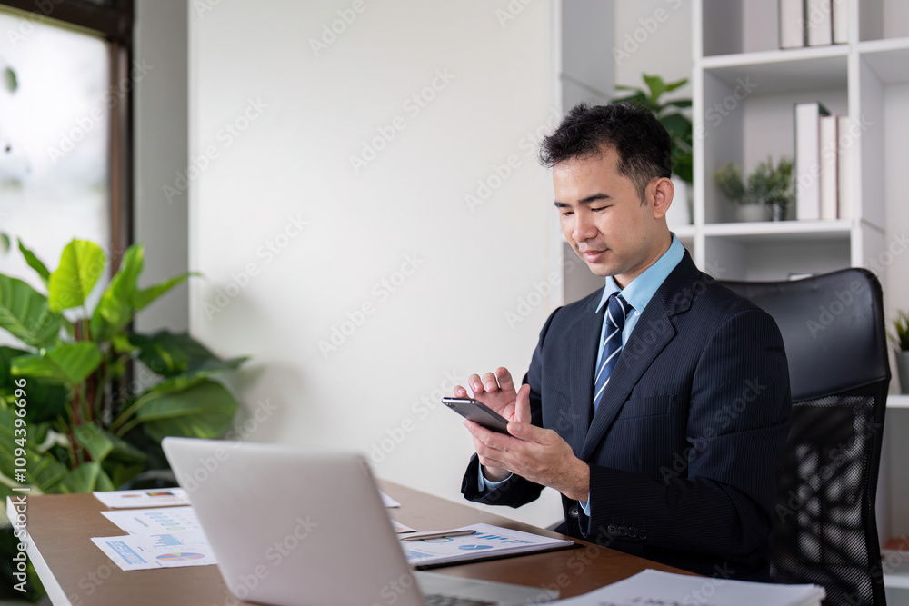 Modern Businessman Utilizing Smartphone and Laptop in Office Modern Businessman Utilizing Smartphone and Laptop in Office