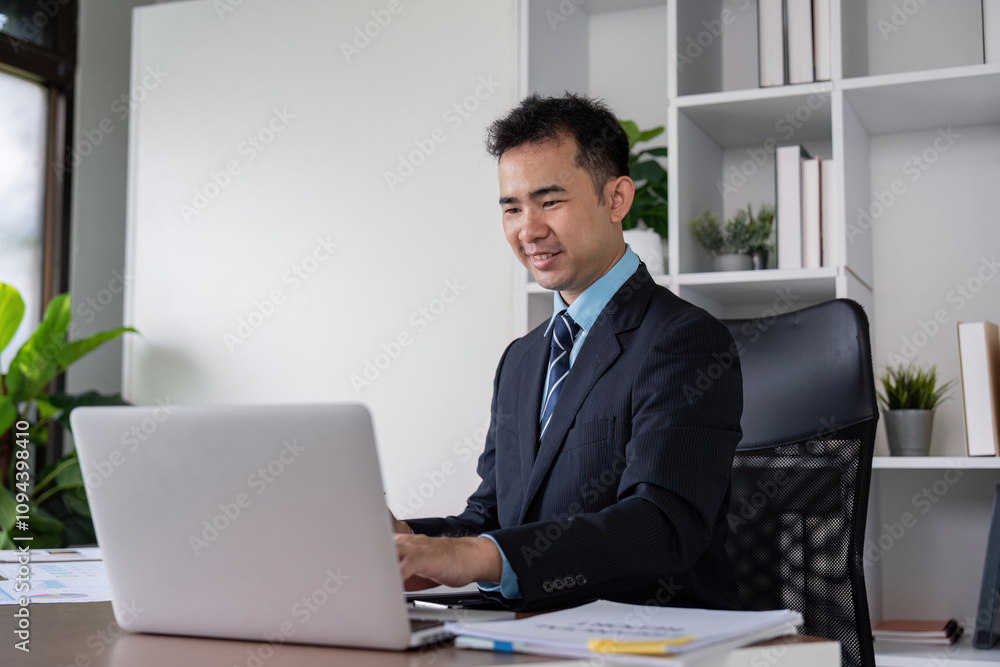 Businessman Smiling While Working on Laptop in Office Businessman Smiling While Working on Laptop in Office