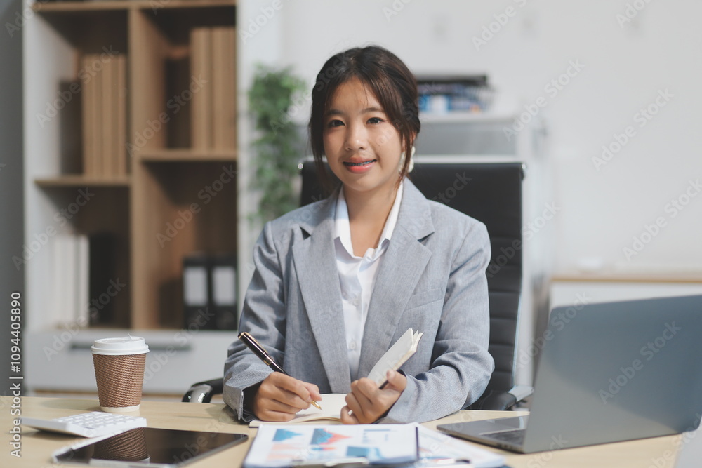 Successful Asian businesswoman smiling using laptop computer and holding coffee cup at office. Confident Asia businesswoman sitting happily in the office. Successful Asian businesswoman smiling using laptop computer and holding coffee cup at office. Confident Asia businesswoman sitting happily in the office.