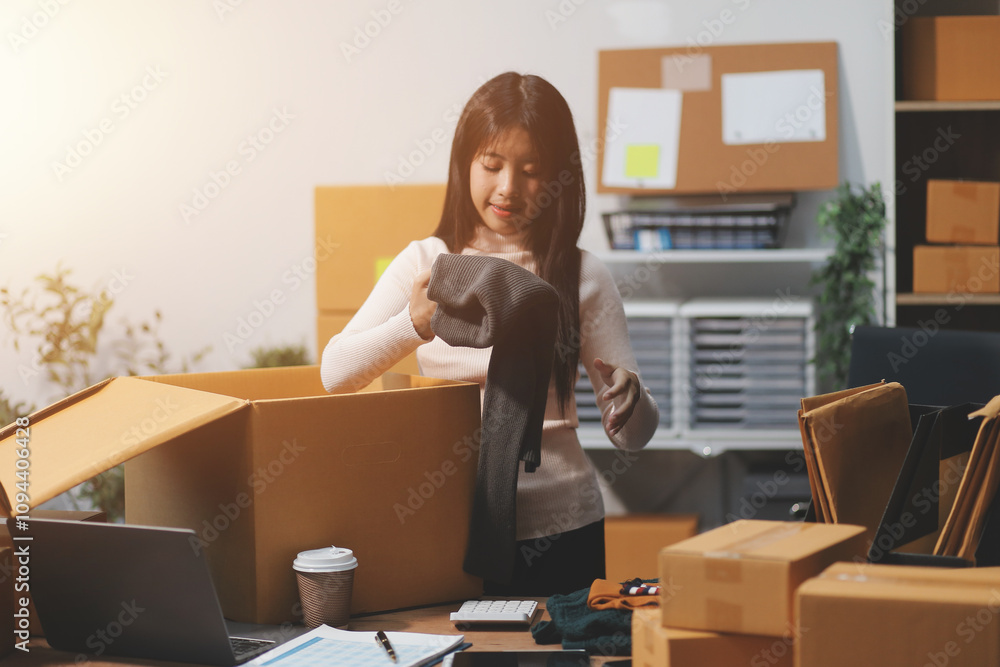 Startup SME small business entrepreneur of freelance Asian woman wearing apron using laptop and box to receive and review orders online to prepare to pack sell to customers, online sme business ideas. Startup SME small business entrepreneur of freelance Asian woman wearing apron using laptop and box to receive and review orders online to prepare to pack sell to customers, online sme business ideas.