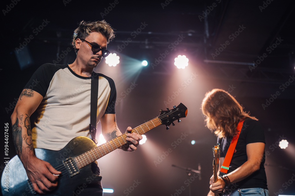 Obraz premium Guitarists playing electric guitars on stage during concert