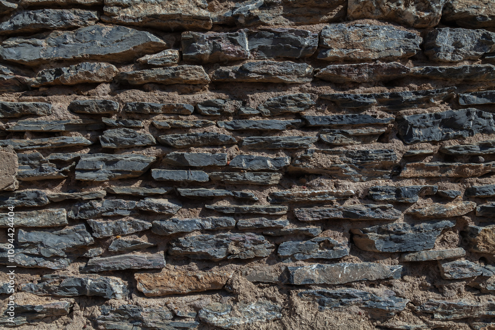 Old ruined masonry made of gray natural stone of different sizes and shapes. Background for design. Old ruined masonry made of gray natural stone of different sizes and shapes. Background for design.