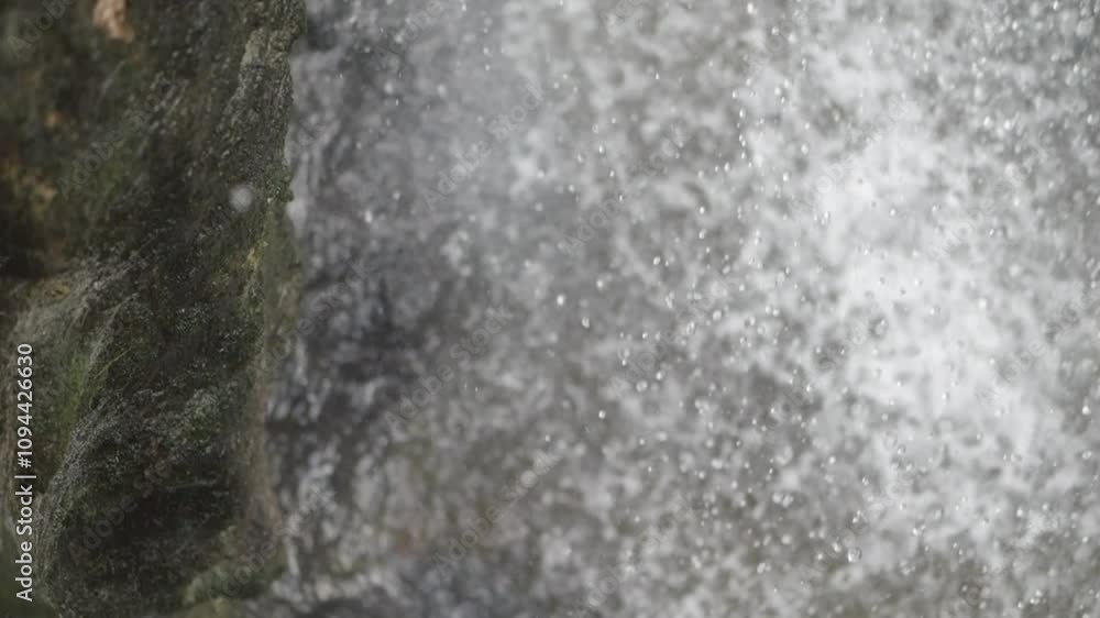 Pristine water droplets fall from rocks in slow motion, each drop glistening. A waterfall cascades in the background, symbolizing purity and tranquility. Pristine water droplets fall from rocks in slow motion, each drop glistening. A waterfall cascades in the background, symbolizing purity and tranquility.