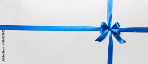 Top view of blue ribbon rolled and blue bow isolated on colored background. Flat lay with copy space photo