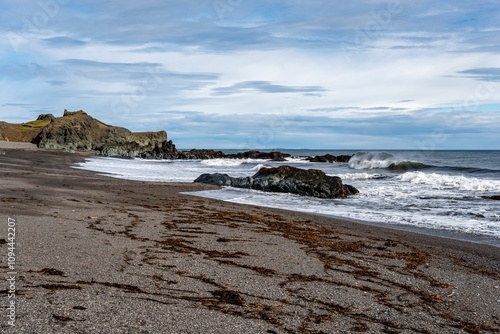 Rocky coastline with crashing waves and sandy beach.