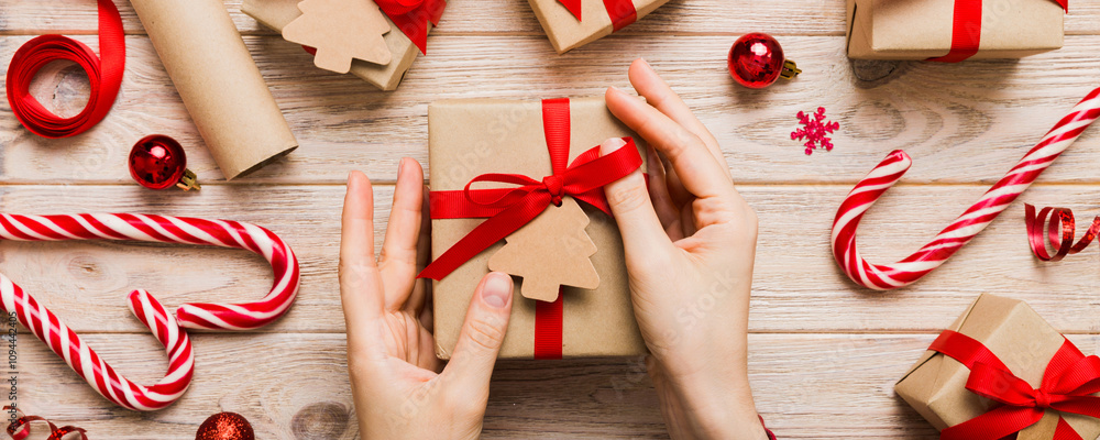 Fototapeta premium Woman hands holding gift box, preparing surprise for holiday, top view, Christmas and New Year concept