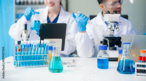 Scientists in lab coats collaborating with test tubes, flasks, and microscopes in a modern lab.