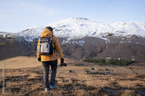 Persona de viaje Hombre de espaldas de viaje en Islandia con cámara de fotos con montañas nevadasen Islandia con cámara de fotos