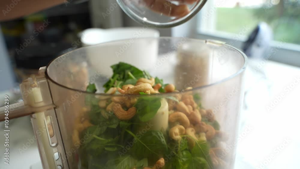 Chef putting bowl full of cashews in blender equipped by pudina leaves. Chef putting bowl full of cashews in blender equipped by pudina leaves.