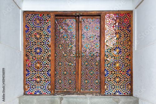 Intricately designed wooden door featuring colorful stained glass leads into Shaki Khans Palace, showcasing traditional Azerbaijani architecture and artistry