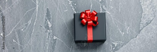 Black gift box with red bow on sleek black stone background, perfect for luxury holiday gifts or special occasions,  bow, gift,  luxury photo