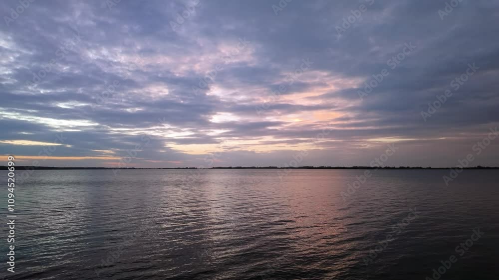 View of Lake Tisza and the surrounding forests in the distance during dusk with moving clouds at Abadszalok, Hungary. View of Lake Tisza and the surrounding forests in the distance during dusk with moving clouds at Abadszalok, Hungary.