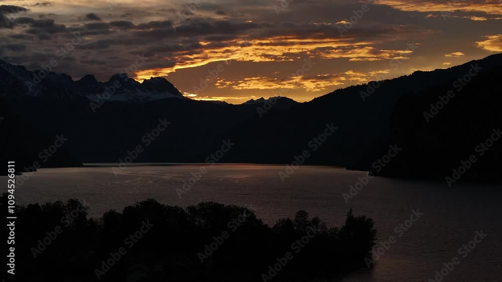 The sun shines through clouds at sunset over a lake in a valley. The mountains of the Swiss Alps in a romantic time The sun shines through clouds at sunset over a lake in a valley. The mountains of the Swiss Alps in a romantic time