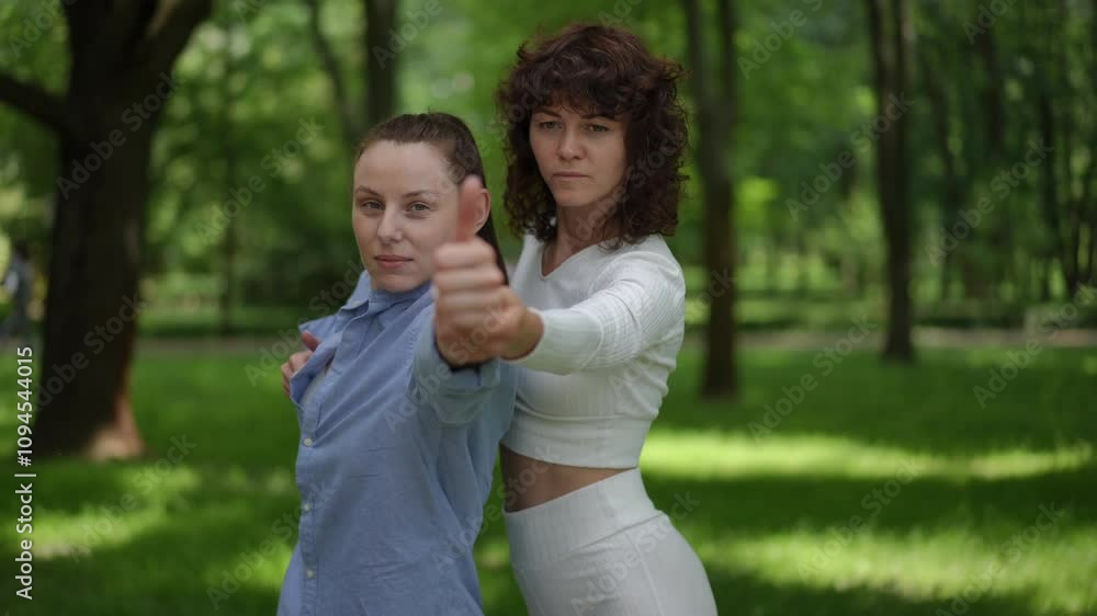 A yoga teacher dressed in white guides a student during an outdoor yoga session. The duo exudes focus and harmony, practicing a confident pose amidst lush greenery. This serene environment fosters A yoga teacher dressed in white guides a student during an outdoor yoga session. The duo exudes focus and harmony, practicing a confident pose amidst lush greenery. This serene environment fosters