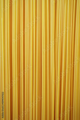 Long strands of yellow pasta displayed against a neutral background for culin...