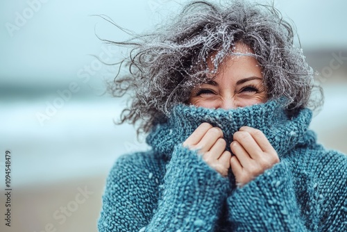 Standing at the seaside is a middle-aged grey-haired woman smiling confidently