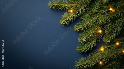 Fresh green pine branches adorned with warm, glowing lights during the holida...