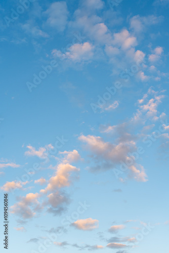 Blue sky and floating cotton clouds in sunlight