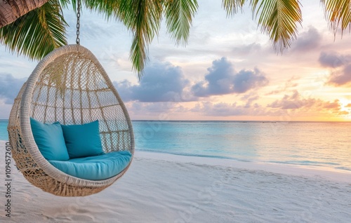 Tranquil beach setting with a hanging chair by the water at sunset