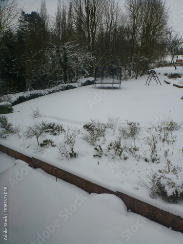 Deep snow in an English garden in winter with trees